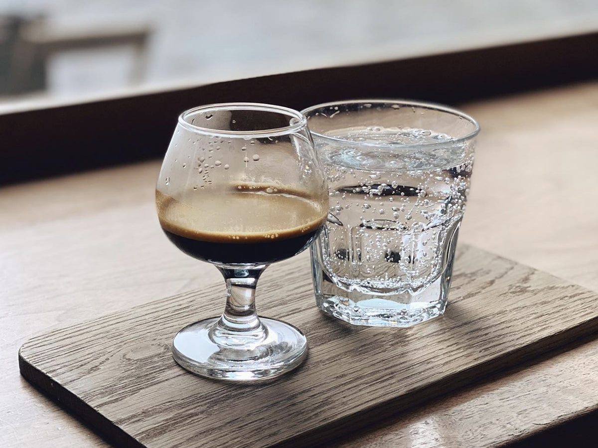 Cups of espresso and sparkling water served on a board