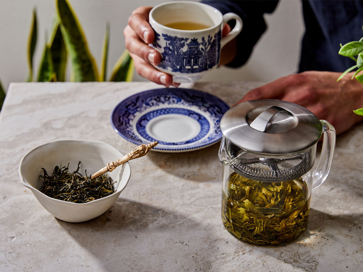 tea leaves steeping next to a cup of tea